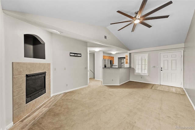 unfurnished living room with light carpet, a fireplace, ceiling fan, and vaulted ceiling