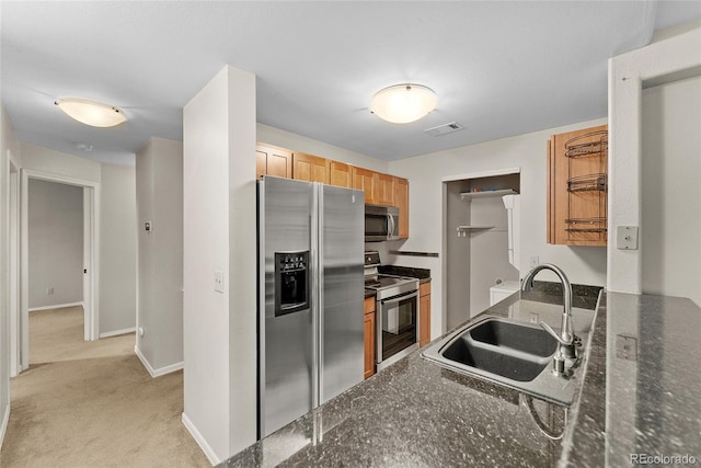 kitchen featuring dark stone counters, light carpet, appliances with stainless steel finishes, and sink