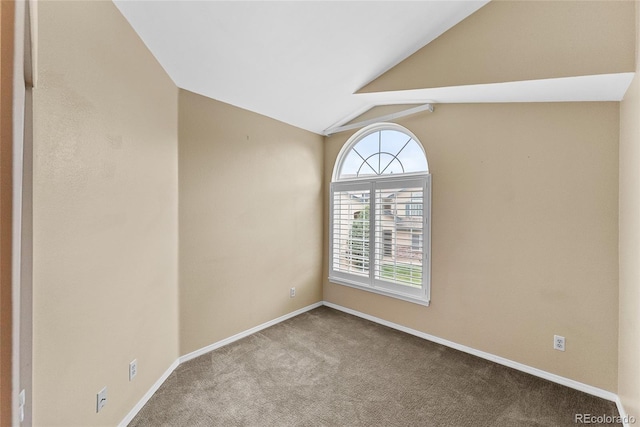 carpeted spare room featuring vaulted ceiling