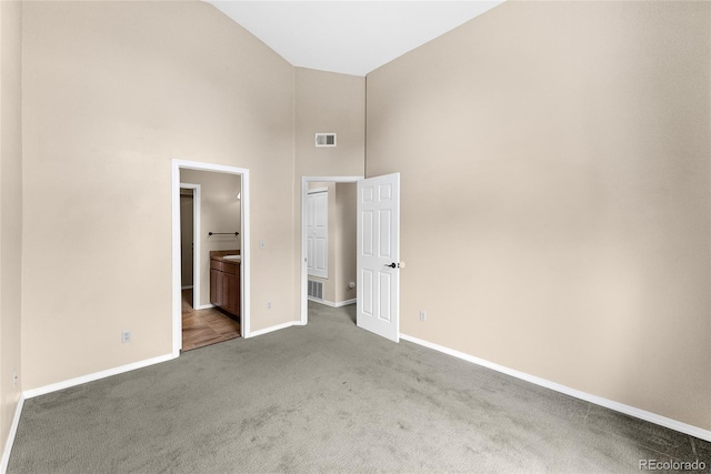 unfurnished bedroom with light carpet, ensuite bath, and high vaulted ceiling