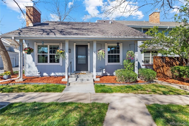 view of front of home featuring fence, a shingled roof, stucco siding, a chimney, and covered porch