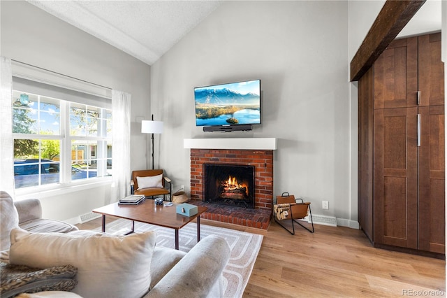 living area with light wood-style floors, baseboards, high vaulted ceiling, and a fireplace