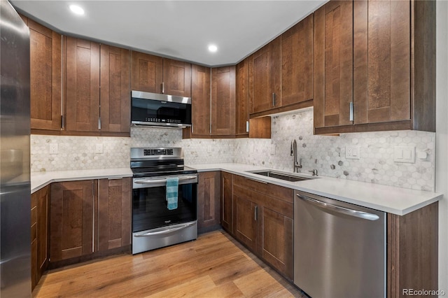 kitchen featuring tasteful backsplash, a sink, light countertops, light wood finished floors, and stainless steel appliances