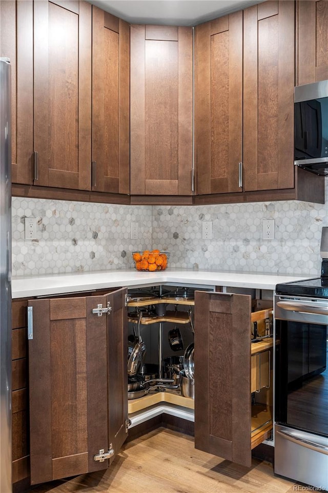bar with appliances with stainless steel finishes, tasteful backsplash, and light wood-type flooring