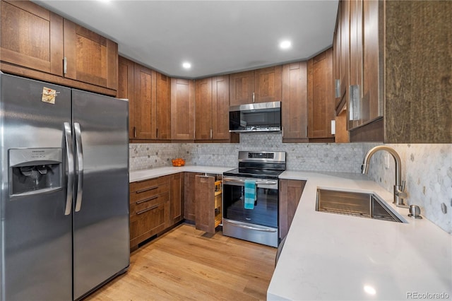 kitchen featuring a sink, appliances with stainless steel finishes, light wood-style flooring, and light countertops