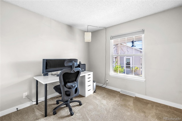 carpeted office with a textured ceiling, baseboards, and visible vents