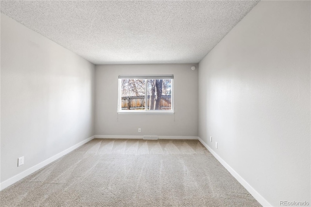 carpeted spare room with visible vents, a textured ceiling, and baseboards