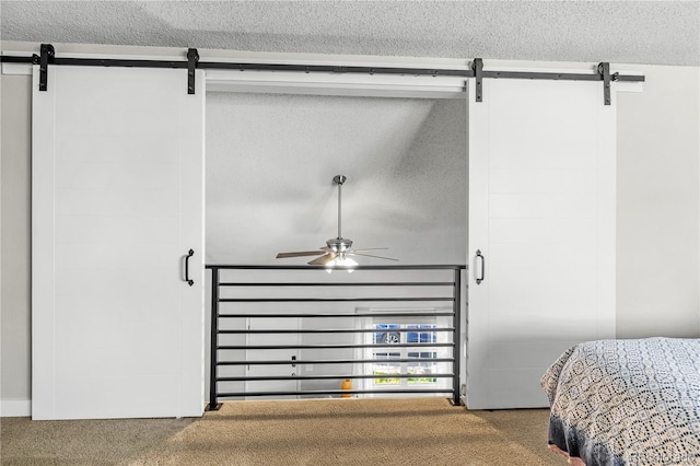 bedroom with a textured ceiling, carpet flooring, and a barn door