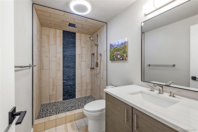 bathroom featuring vanity, tile patterned flooring, a tile shower, and toilet