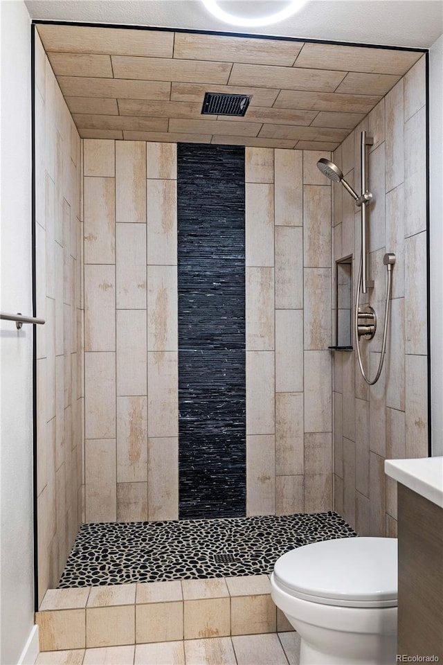 bathroom with a tile shower, tile patterned flooring, vanity, toilet, and visible vents