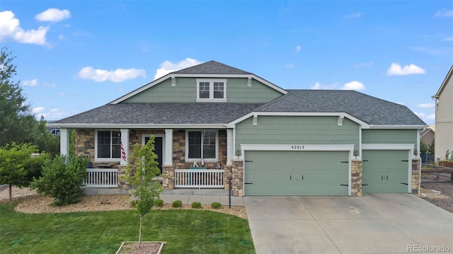 view of front of house featuring a garage, a front yard, and covered porch