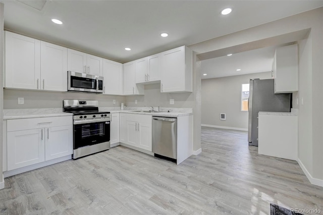 1216 Norwood Ave, Colorado Springs, CO 80905 - kitchen with appliances with stainless steel finishes, light countertops, white cabinets, light wood finished floors, and recessed lighting