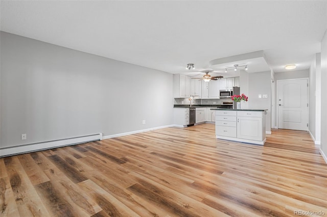 kitchen with appliances with stainless steel finishes, white cabinetry, decorative backsplash, ceiling fan, and light hardwood / wood-style floors