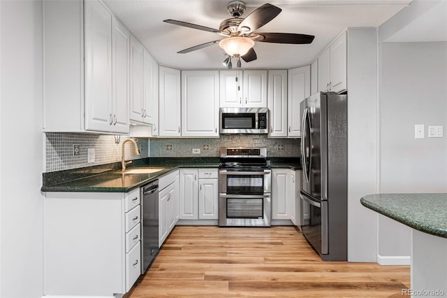 kitchen featuring white cabinetry, stainless steel appliances, sink, and light hardwood / wood-style flooring