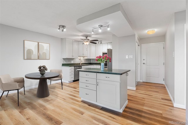 kitchen featuring sink, appliances with stainless steel finishes, white cabinetry, light hardwood / wood-style floors, and decorative backsplash