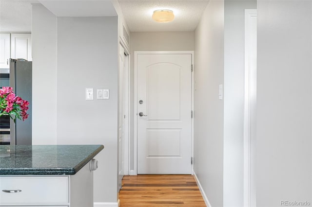 hallway with light hardwood / wood-style flooring and a textured ceiling