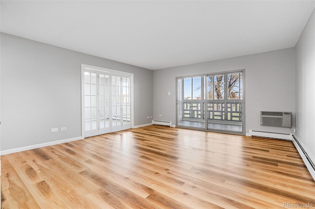 empty room featuring baseboard heating, a wall unit AC, and light wood-type flooring