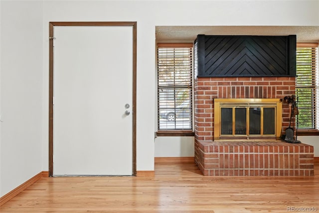 10102 W Ida Ave Unit 214, Littleton, CO 80127 - unfurnished living room featuring a brick fireplace, baseboards, wood finished floors, and healthy amount of natural light