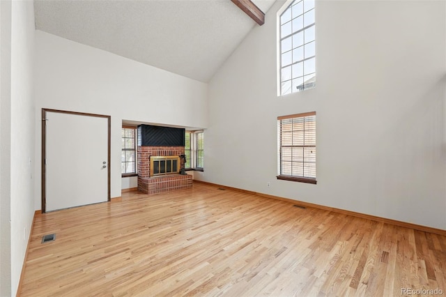 10102 W Ida Ave Unit 214, Littleton, CO 80127 - unfurnished living room featuring high vaulted ceiling, a brick fireplace, wood finished floors, baseboards, and beamed ceiling