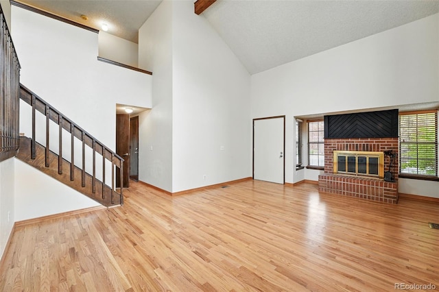 10102 W Ida Ave Unit 214, Littleton, CO 80127 - unfurnished living room with high vaulted ceiling, a fireplace, wood finished floors, baseboards, and stairs