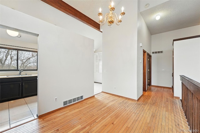 10102 W Ida Ave Unit 214, Littleton, CO 80127 - unfurnished dining area with a sink, light wood-style floors, a chandelier, baseboards, and beam ceiling
