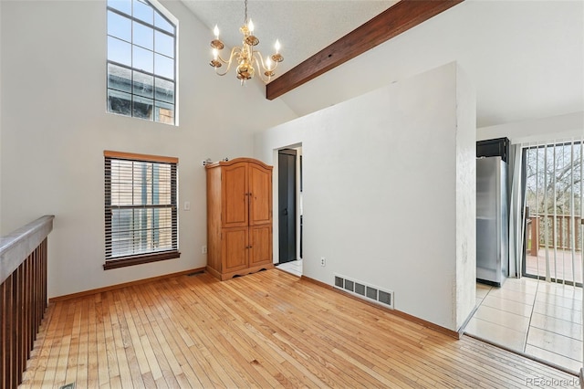 10102 W Ida Ave Unit 214, Littleton, CO 80127 - unfurnished living room featuring light wood-type flooring, a chandelier, plenty of natural light, high vaulted ceiling, and beamed ceiling