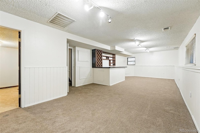 10102 W Ida Ave Unit 214, Littleton, CO 80127 - basement featuring carpet, a textured ceiling, a wainscoted wall, rail lighting, and bar area