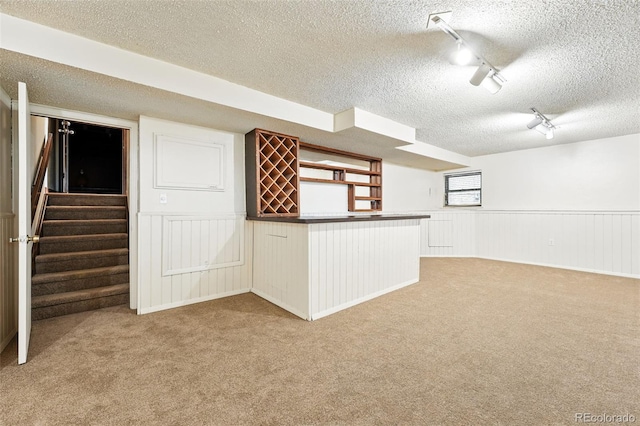 10102 W Ida Ave Unit 214, Littleton, CO 80127 - below grade area featuring a textured ceiling, carpet flooring, wainscoting, a bar, and track lighting