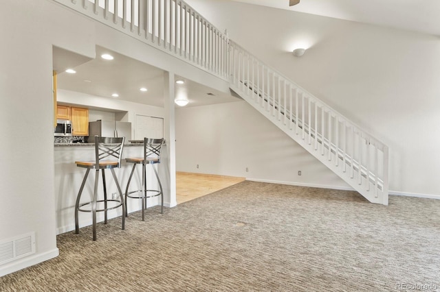 11085 Huron St Unit 1108, Northglenn, CO 80234 - unfurnished living room featuring carpet floors, a high ceiling, recessed lighting, and stairs