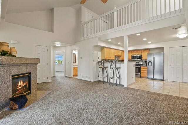 11085 Huron St Unit 1108, Northglenn, CO 80234 - living room featuring light colored carpet, a ceiling fan, high vaulted ceiling, a high end fireplace, and recessed lighting