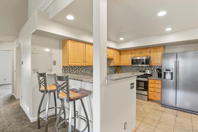 11085 Huron St Unit 1108, Northglenn, CO 80234 - kitchen featuring appliances with stainless steel finishes, decorative backsplash, a breakfast bar area, a peninsula, and recessed lighting