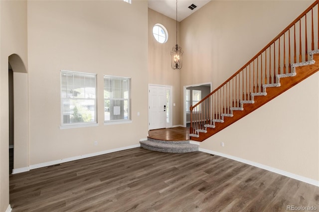 entryway with a towering ceiling and dark wood-type flooring