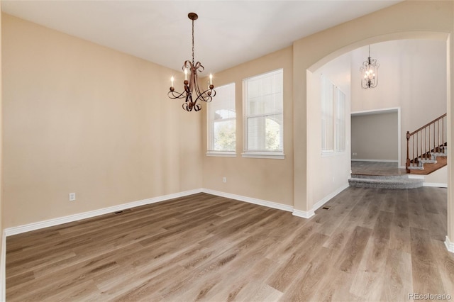 unfurnished room with wood-type flooring and a chandelier