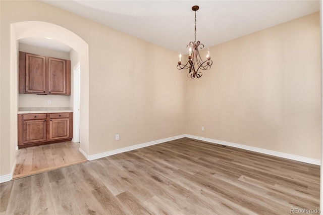 unfurnished dining area with a notable chandelier and wood-type flooring