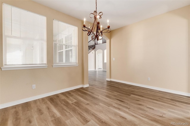 unfurnished dining area with a notable chandelier, a healthy amount of sunlight, and wood-type flooring