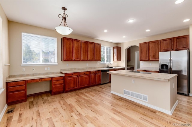 kitchen featuring a healthy amount of sunlight, stainless steel appliances, a center island, and pendant lighting