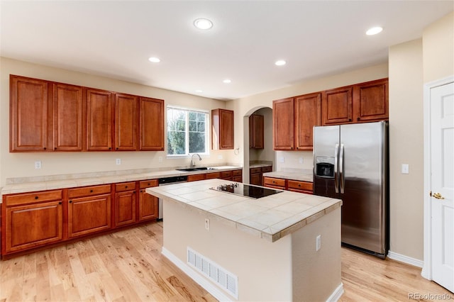 kitchen featuring sink, stainless steel appliances, a center island, and light wood-type flooring