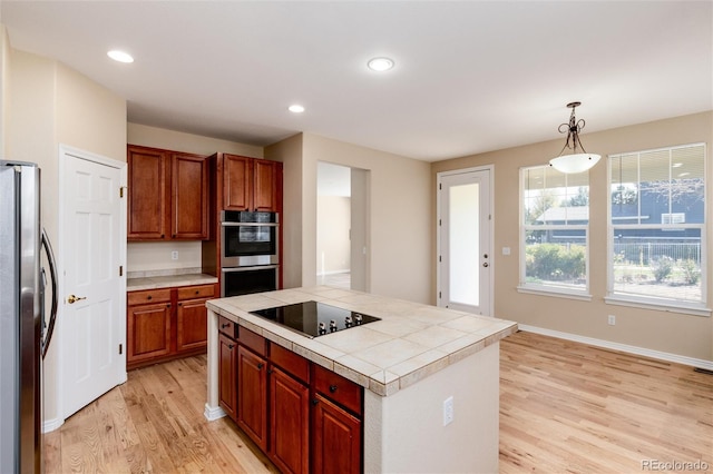 kitchen with a center island, appliances with stainless steel finishes, light hardwood / wood-style flooring, and hanging light fixtures