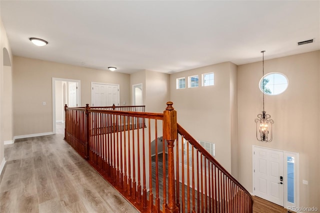 hall featuring hardwood / wood-style floors and a chandelier