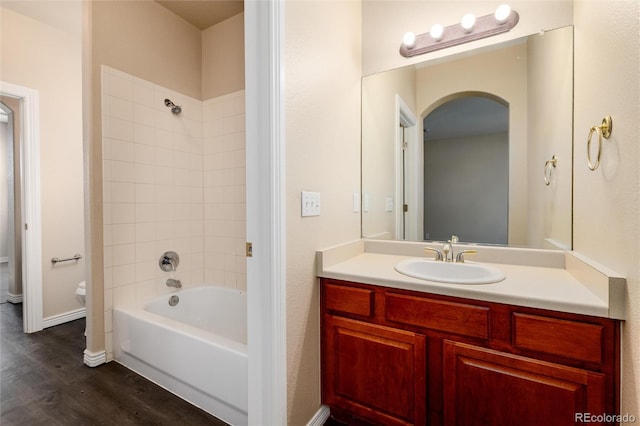 full bathroom featuring toilet, tiled shower / bath combo, vanity, and wood-type flooring