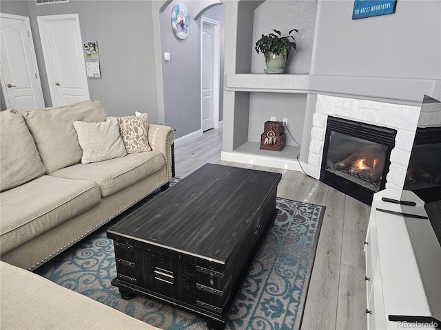 living room featuring built in shelves, wood-type flooring, and a fireplace