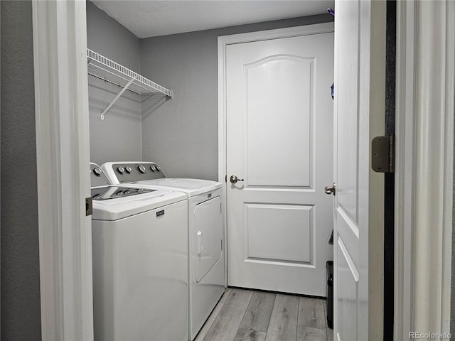 laundry room featuring independent washer and dryer and light hardwood / wood-style floors