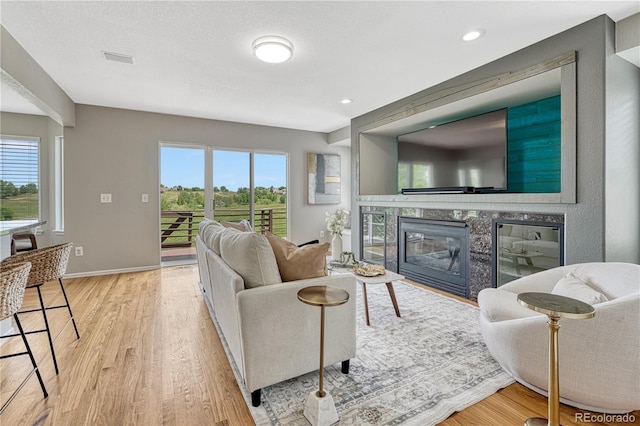 901 Sage Sparrow Cir, Highlands Ranch, CO 80129 - living area with healthy amount of natural light, wood finished floors, a glass covered fireplace, baseboards, and recessed lighting
