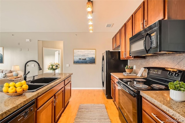 2705 S Danube Way Unit 306, Aurora, CO 80013 - kitchen featuring black appliances, a sink, brown cabinets, light wood-style floors, and backsplash