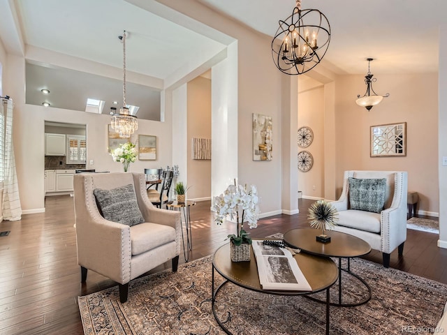 living area with dark wood-style floors, a notable chandelier, high vaulted ceiling, and baseboards