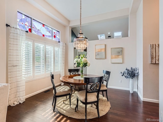 dining area featuring a notable chandelier, dark wood finished floors, lofted ceiling, visible vents, and baseboards