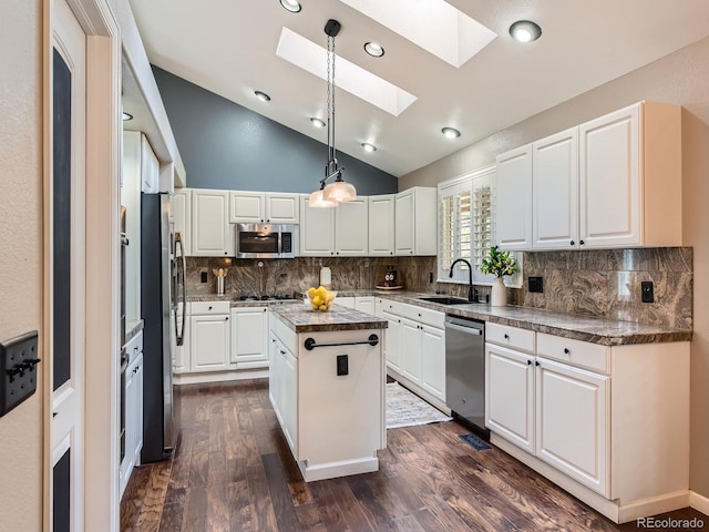 kitchen featuring lofted ceiling with skylight, a kitchen island, appliances with stainless steel finishes, white cabinetry, and a sink