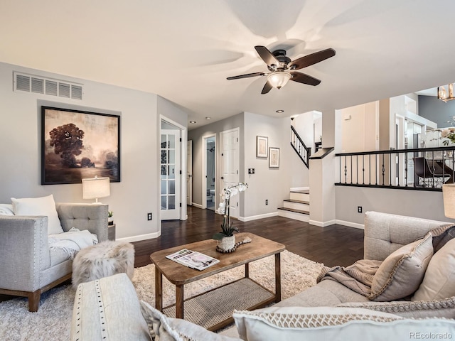 living room featuring baseboards, visible vents, stairway, wood finished floors, and ceiling fan with notable chandelier