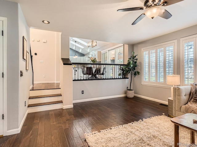 sitting room with stairs, hardwood / wood-style floors, ceiling fan with notable chandelier, and baseboards