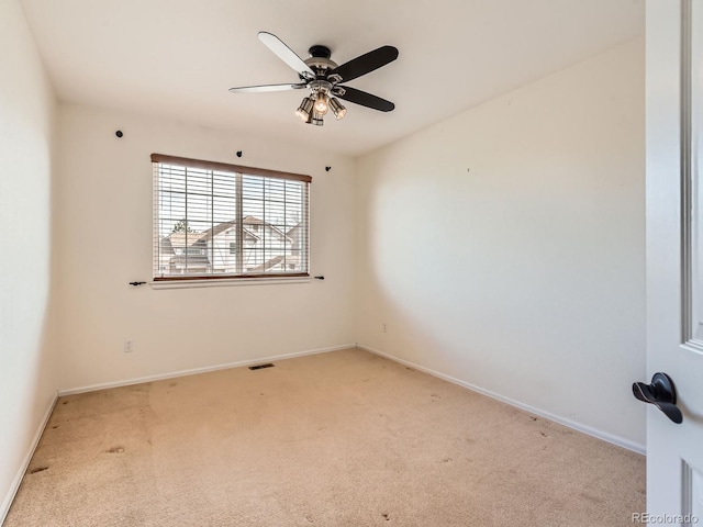 carpeted spare room featuring ceiling fan, visible vents, and baseboards